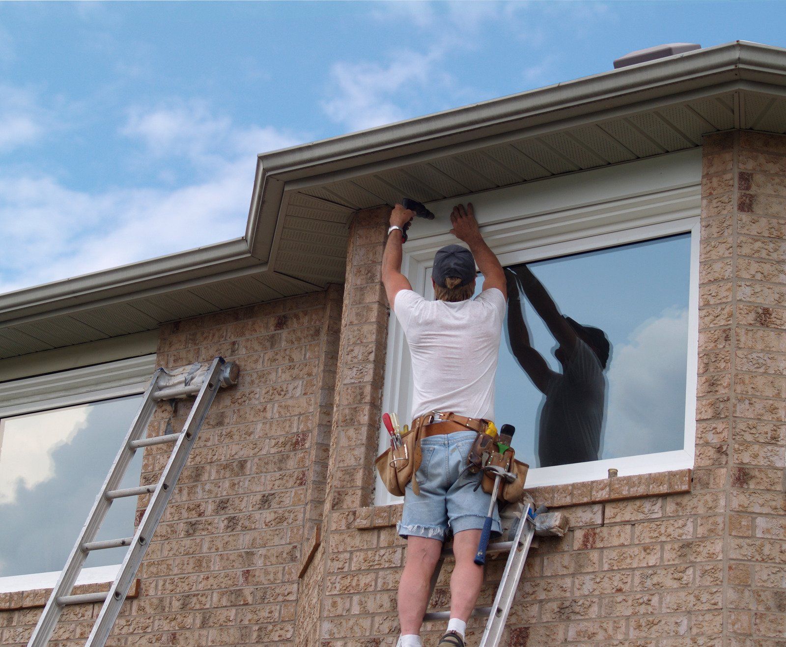 A man standing on a ladder working on a window