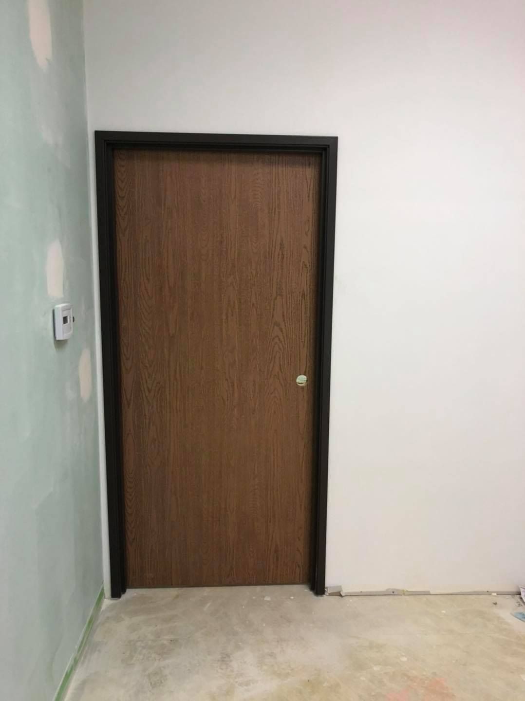 A wooden door is in a room with a white wall.