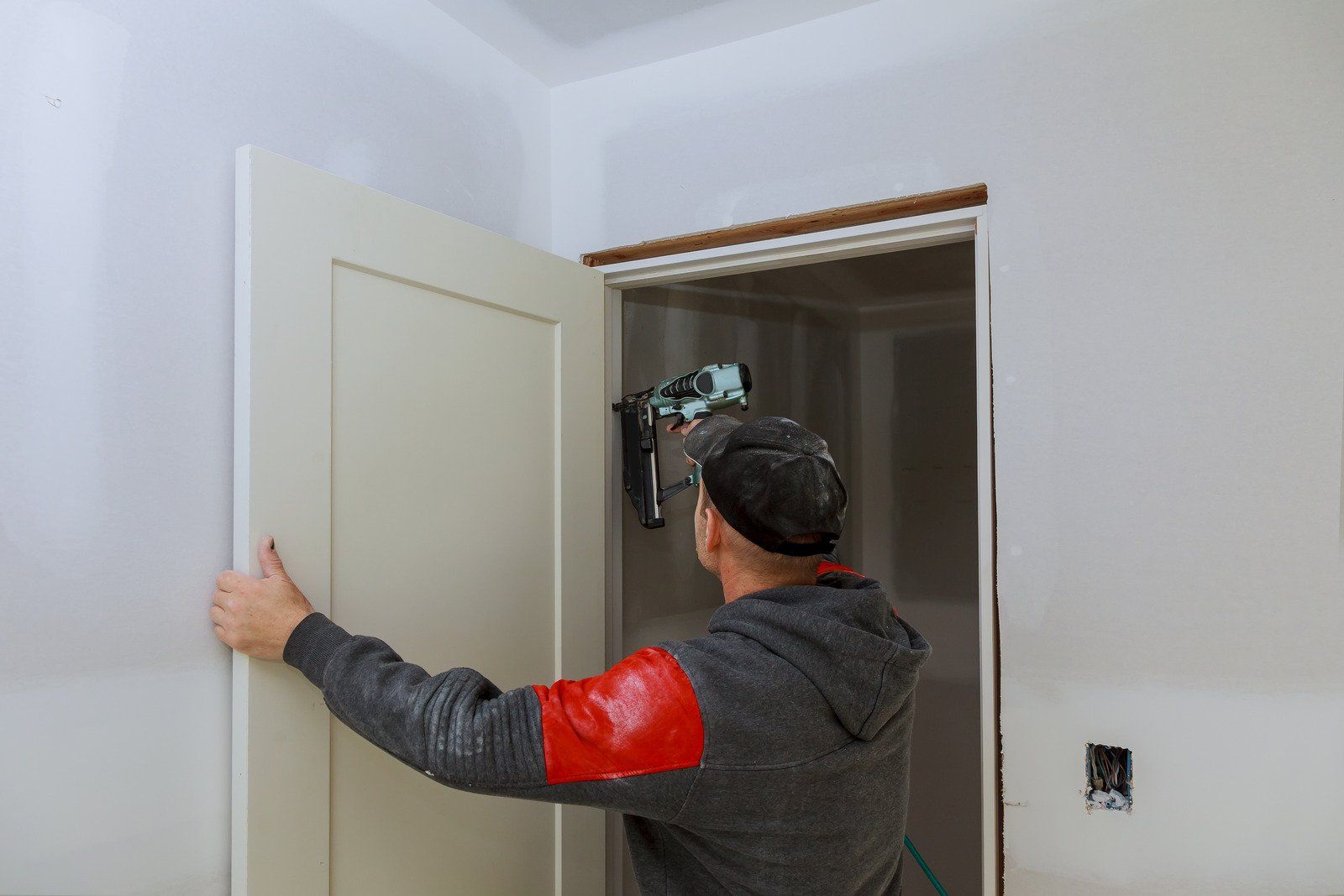 A man is installing a door in a room.