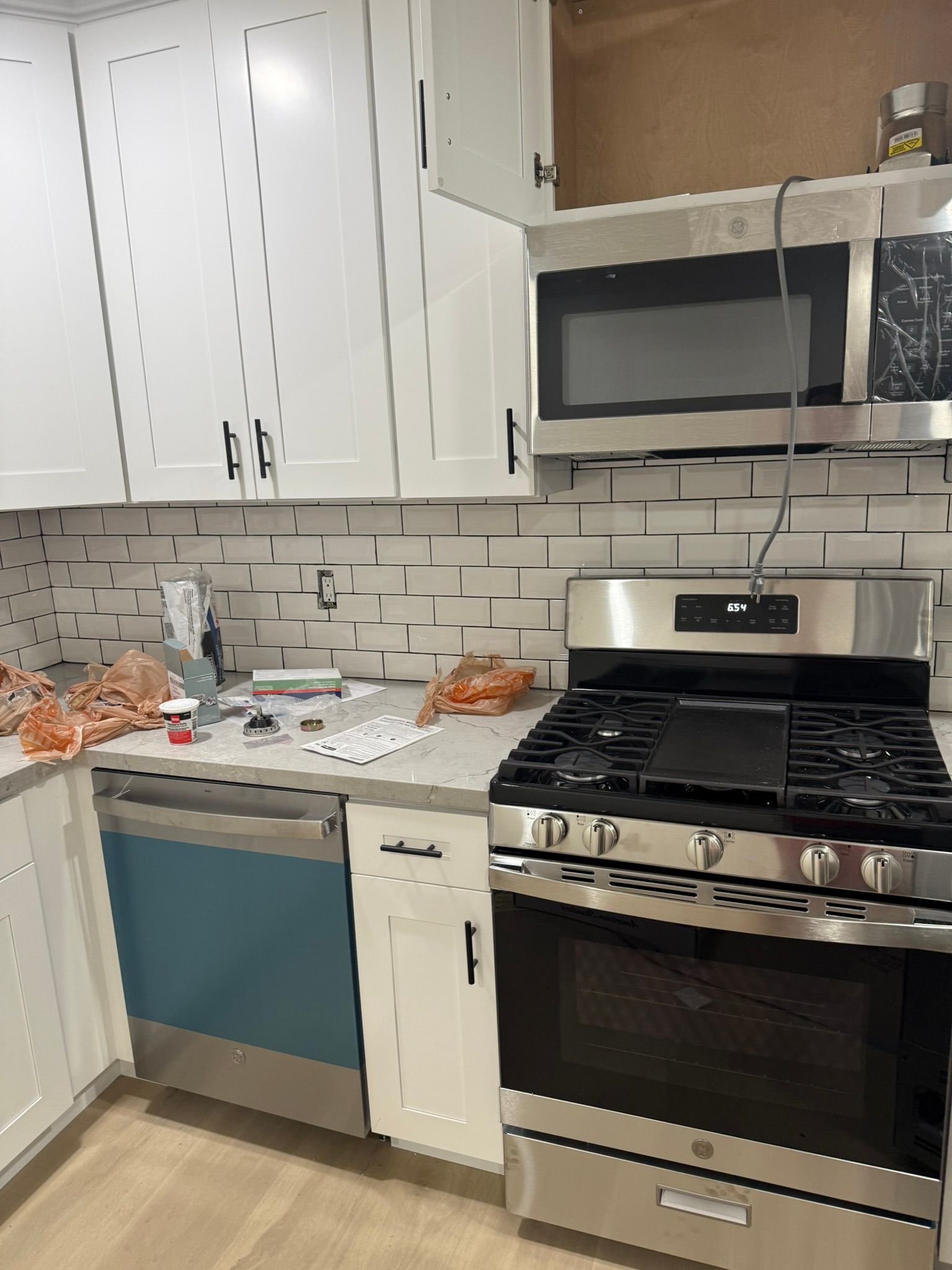 A kitchen with white cabinets, a stainless steel gas range, a matching microwave, and a subway tile backsplash.