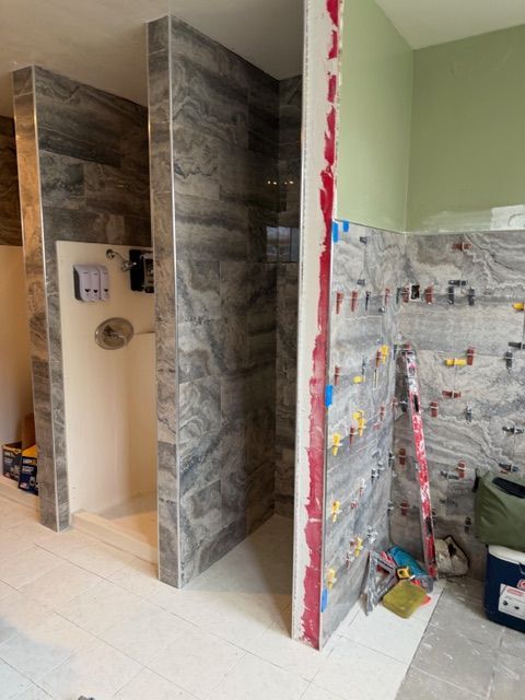 Bathroom under construction with gray tile walls and white floors; partially completed.