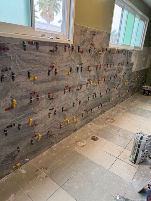 Wall tiling in progress with spacers and leveling system in place.