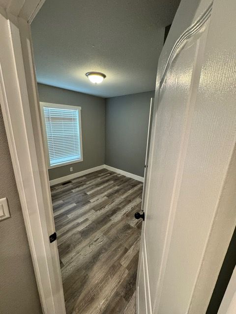 Bedroom interior with gray walls, wood-look flooring, and a window with blinds.
