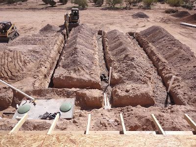 A construction site with a lot of dirt and a bulldozer in the background.