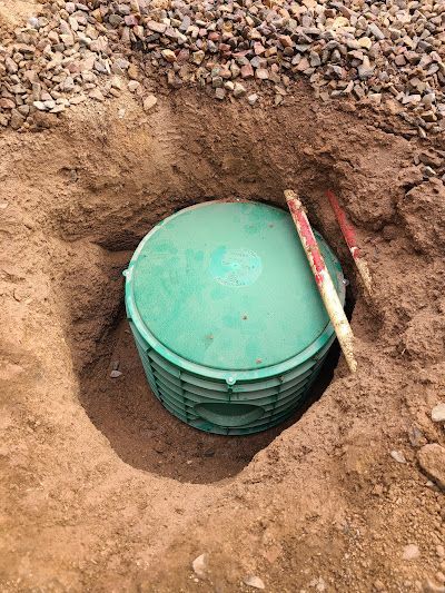 A green container is sitting in a hole in the ground.