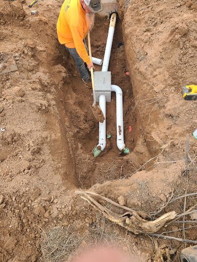 A man is digging a hole in the ground to install a pipe.
