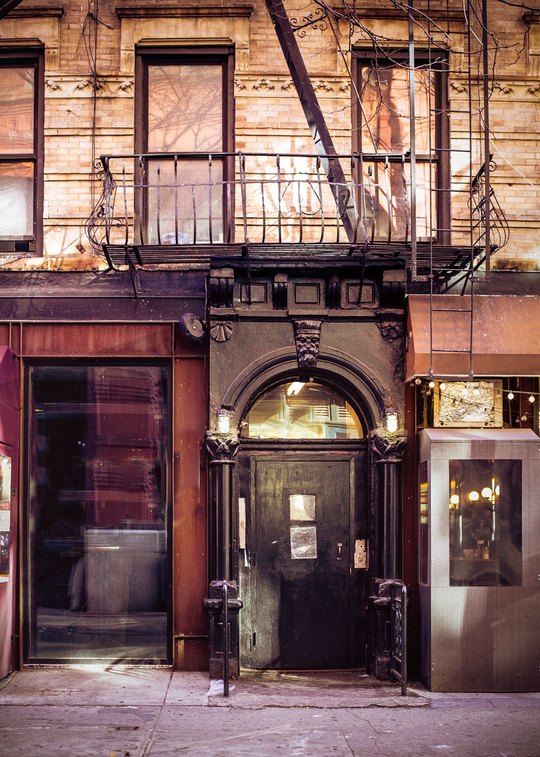 Old brick storefront at night with dark arched doorway and lit windows above