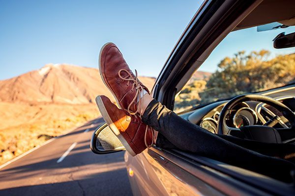 A person is sitting in a car with their feet out the window. | Lex Brodies