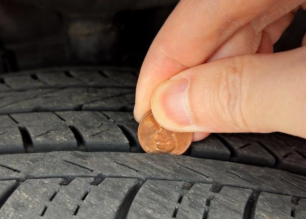 A person is putting a penny into a tire | Lex Brodies