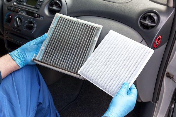 A person wearing blue gloves is holding two air filters in their hands. | Lex Brodies