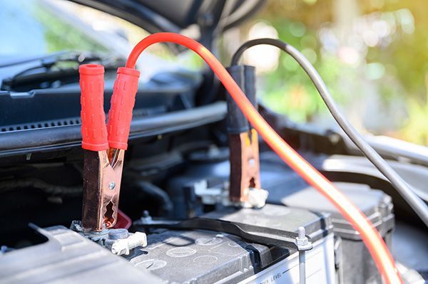 A close up of a car battery being charged with jumper cables. | Lex Brodies