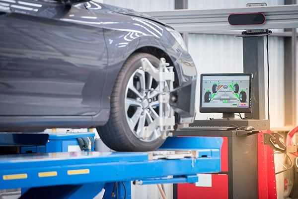 A car is being aligned on a lift in a garage. | Lex Brodies