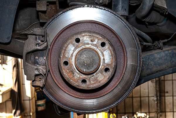 A close up of a brake disc on a car in a garage. | Lex Brodies