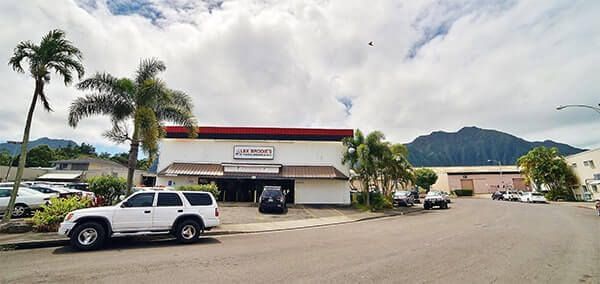 A white suv is parked in front of a building with mountains in the background. | Lex Brodies 