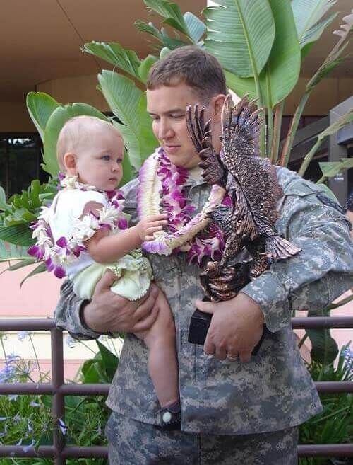 A man in a military uniform is holding a baby and a statue of an eagle | Lex Brodies
