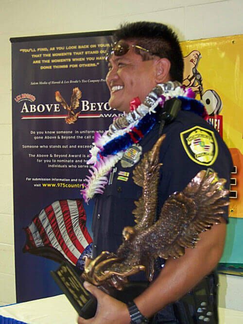 A man holding a trophy in front of a sign that says above beyc | Lex Brodies