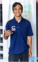A young man wearing a blue polo shirt is standing in front of a poster. | Lex Brodies 