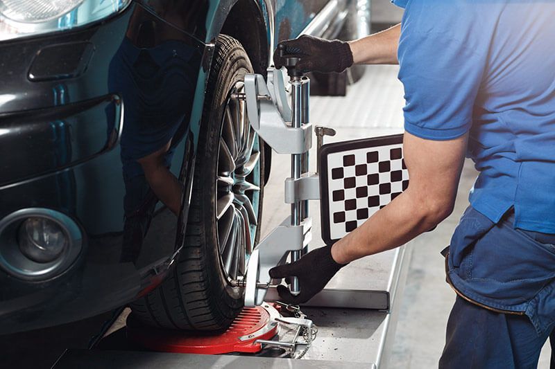 A man is working on a car wheel alignment in a garage. | Lex Brodies