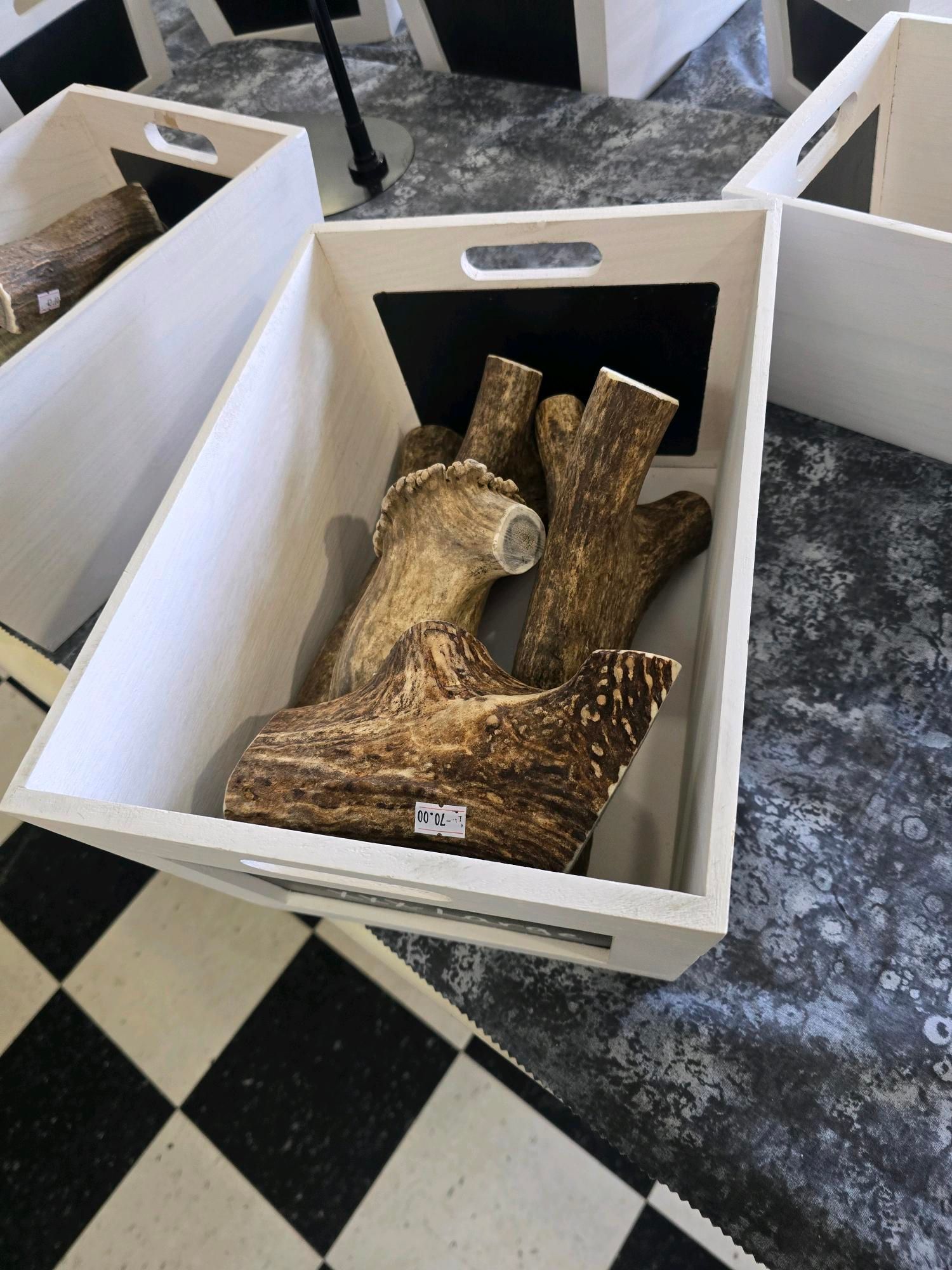 A wooden box filled with deer antlers on a checkered floor