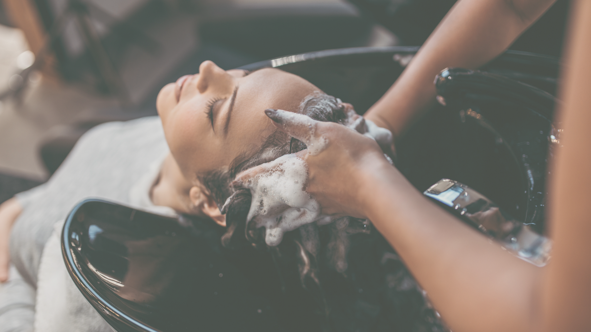 A person getting their hair washed in a sink at a salon.
