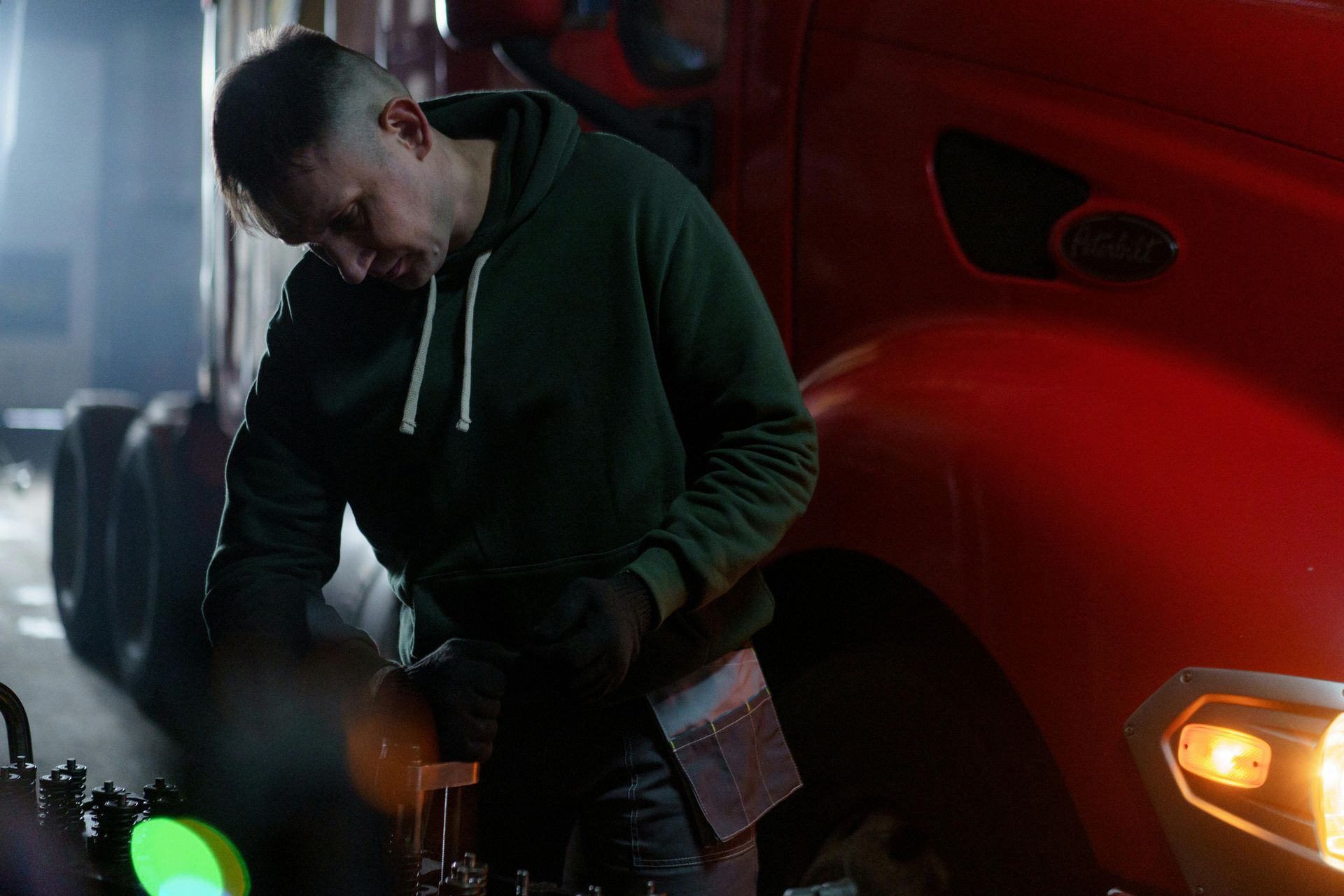A man is working on the engine of a semi truck.