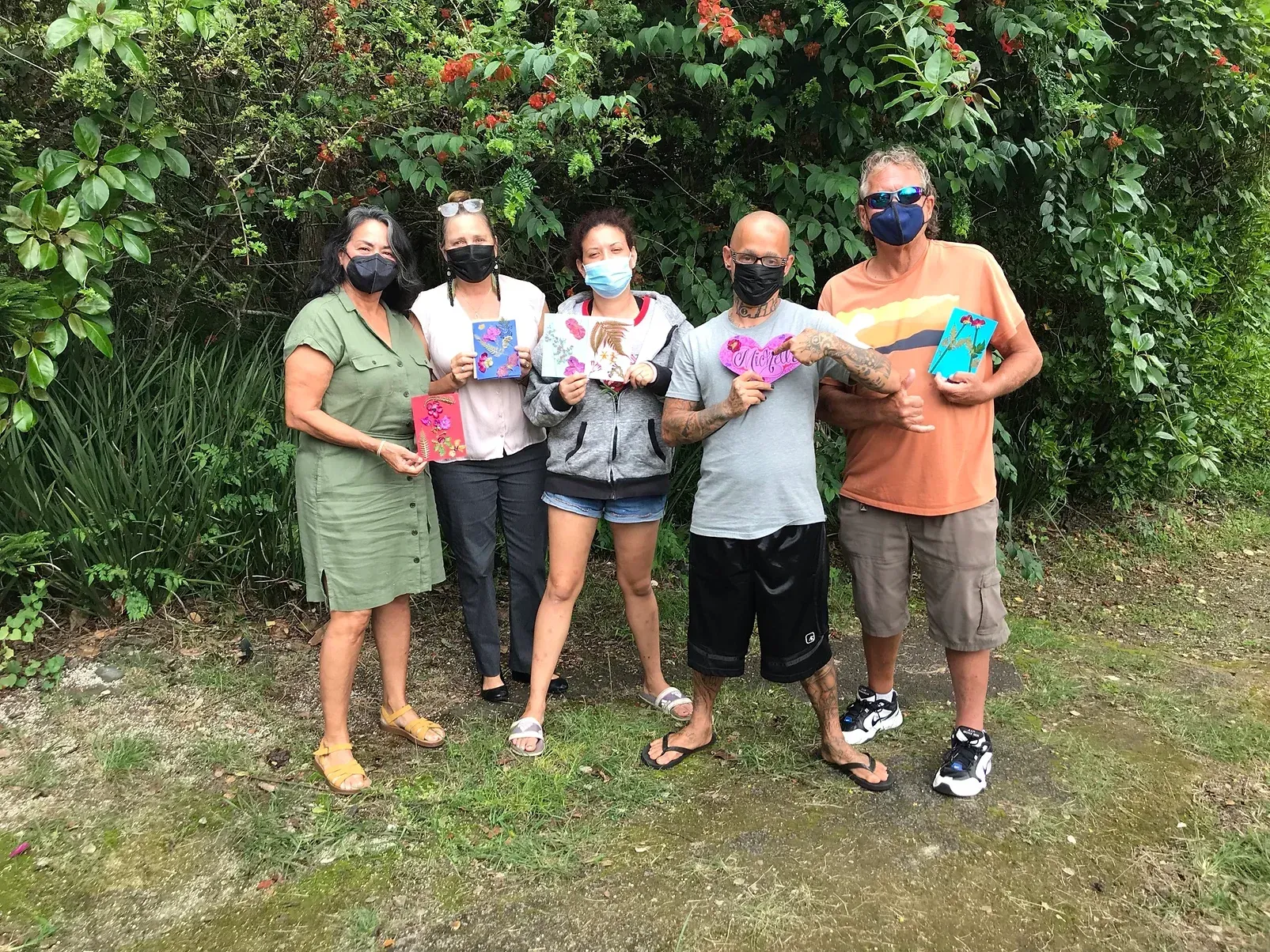 A group of people are standing around a tree in a park.