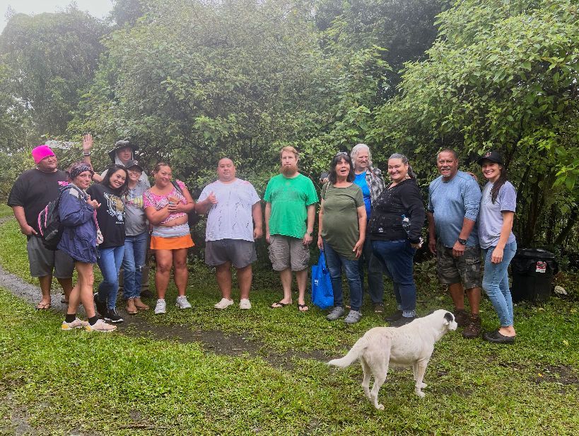 A group of people and a dog are standing in a field.