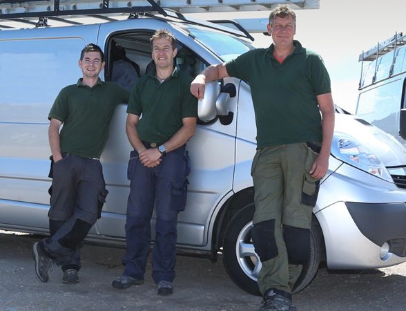 three men standing in front of a silver van