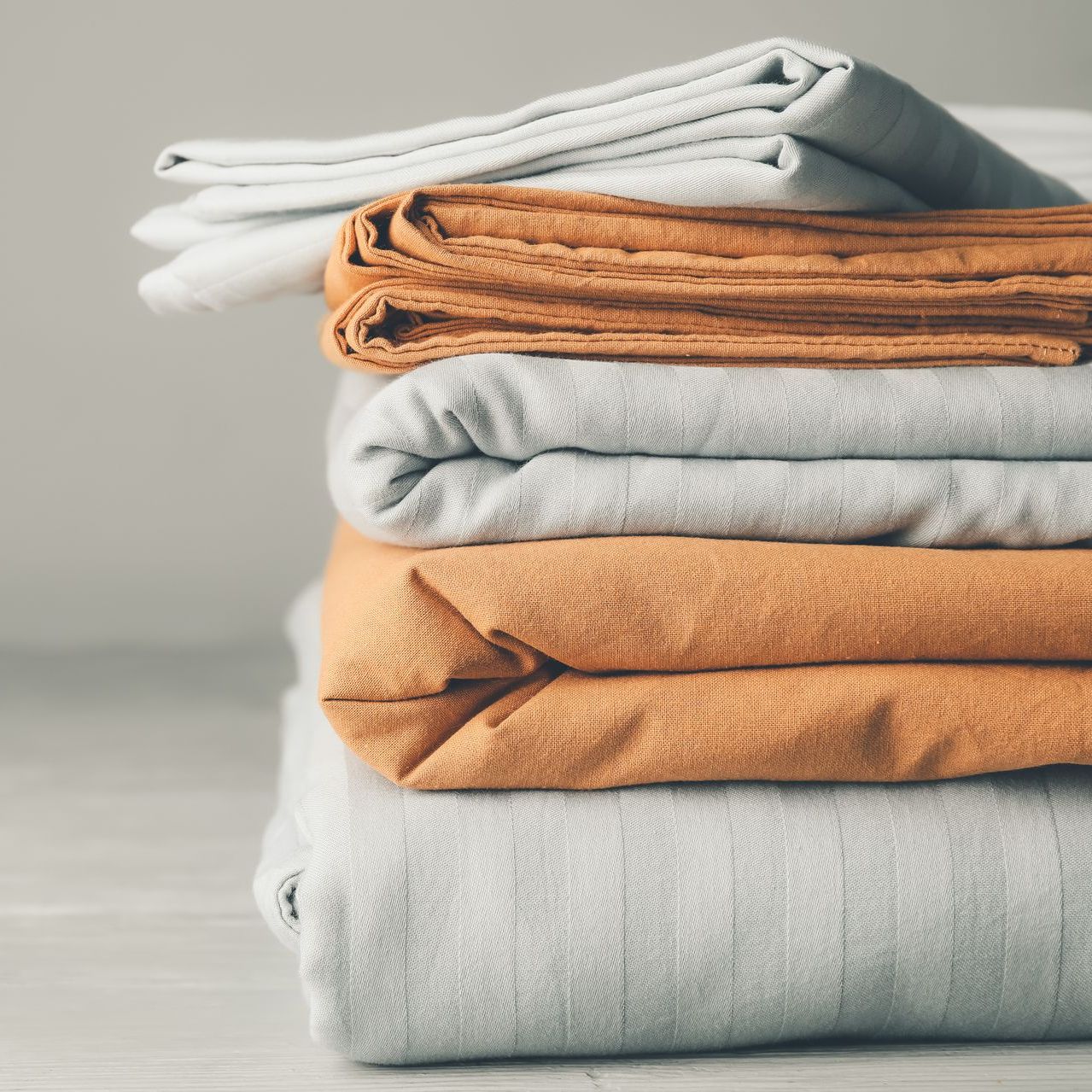 A pile of blankets of different colors are stacked on top of each other on a table.