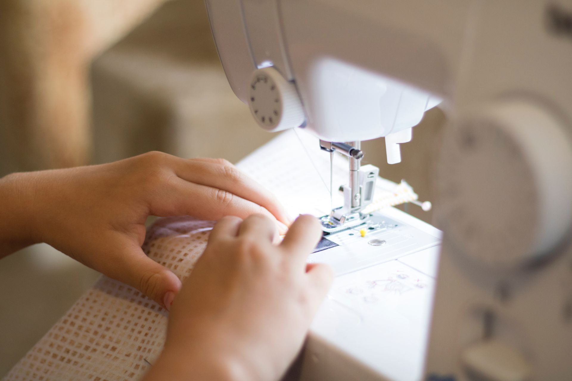 A person is using a sewing machine to sew a piece of fabric.