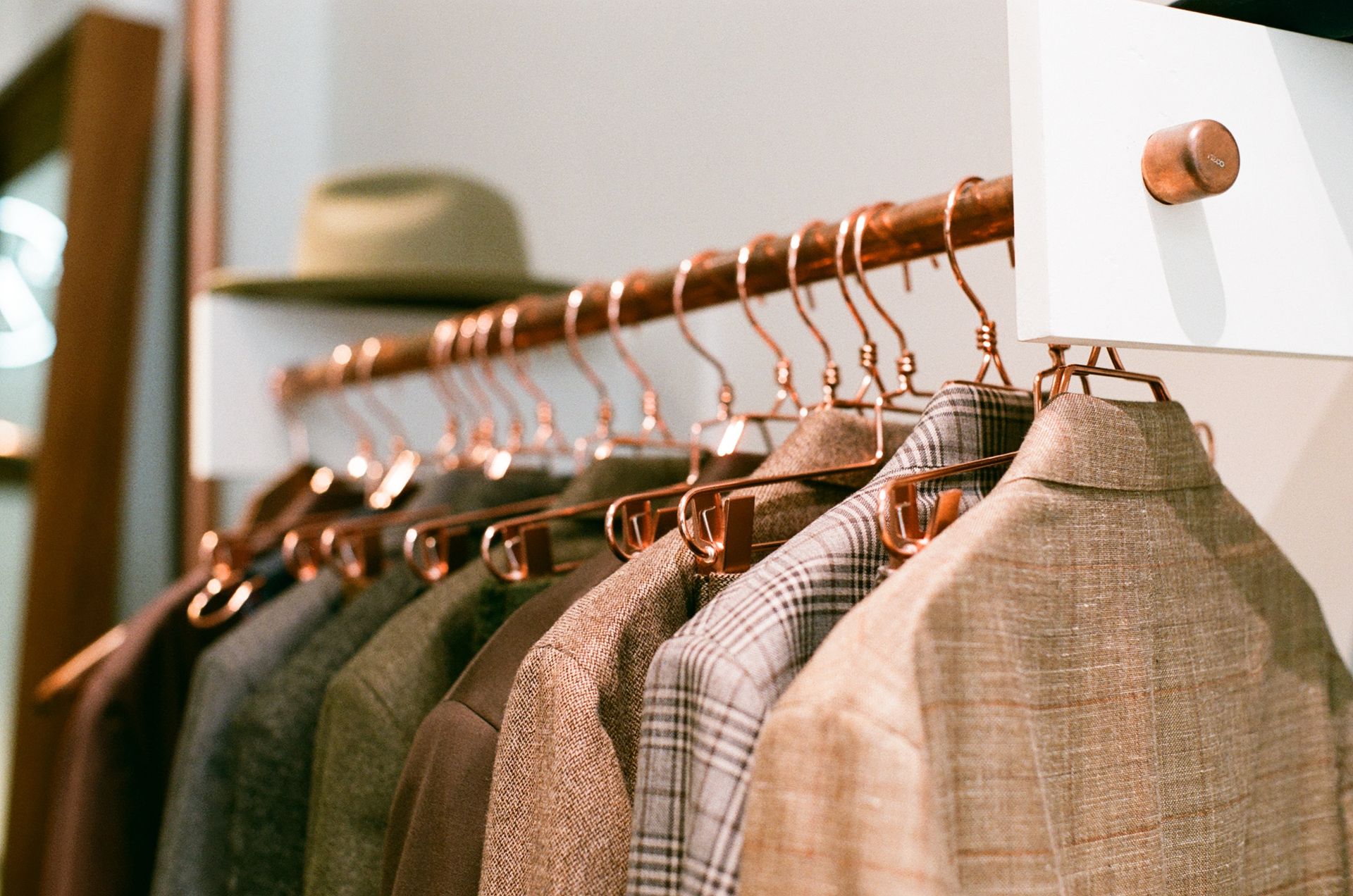A row of jackets hanging on a rack in a closet.