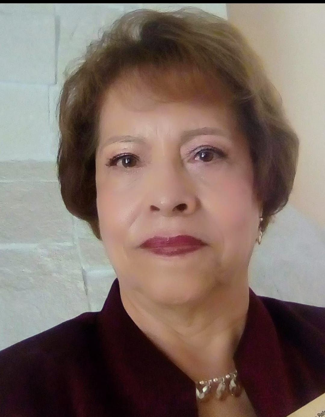 Woman with short brown hair wearing a burgundy blazer, looking at the camera.