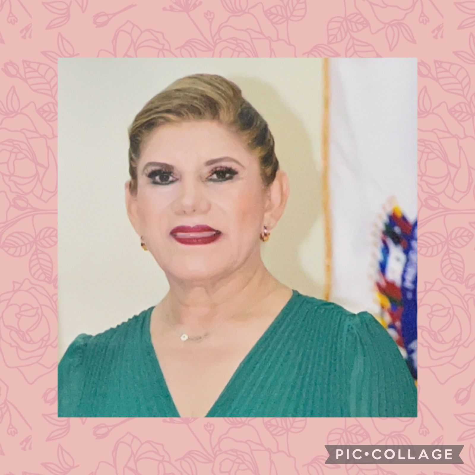 Woman in green top with makeup, standing in a room. Pink floral border.