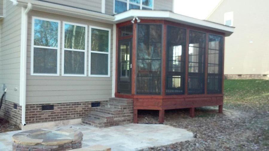 A screened in porch with a fire pit in the backyard of a house.