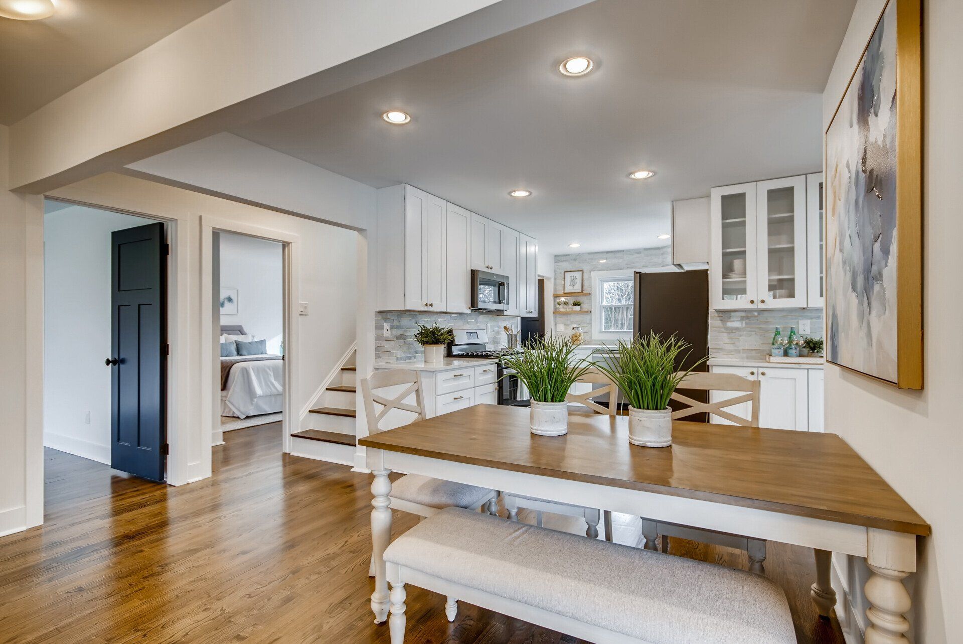 A dining room table and bench in a house with a kitchen in the background.