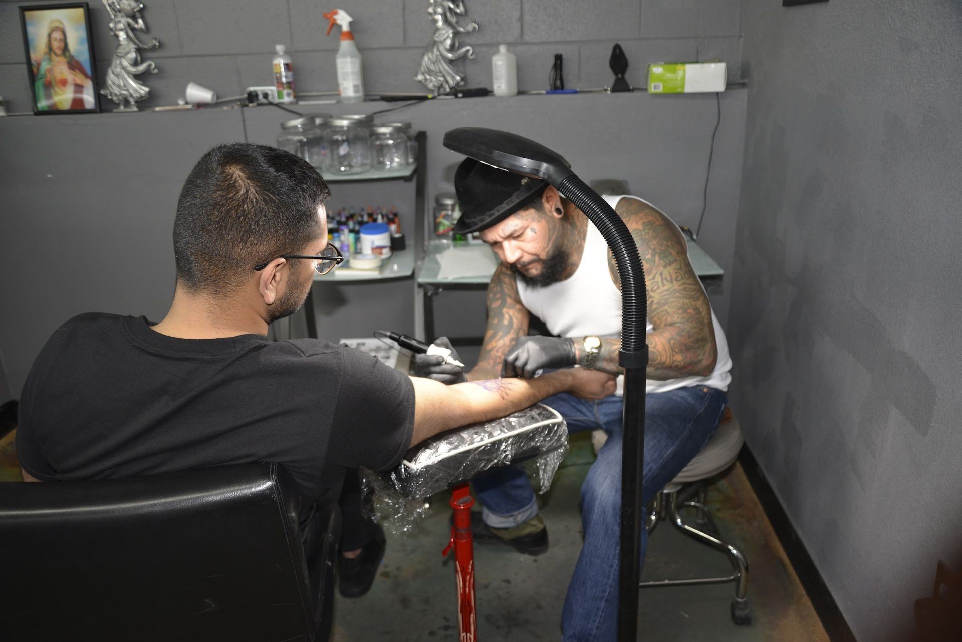 A man is getting a tattoo on another man 's arm.