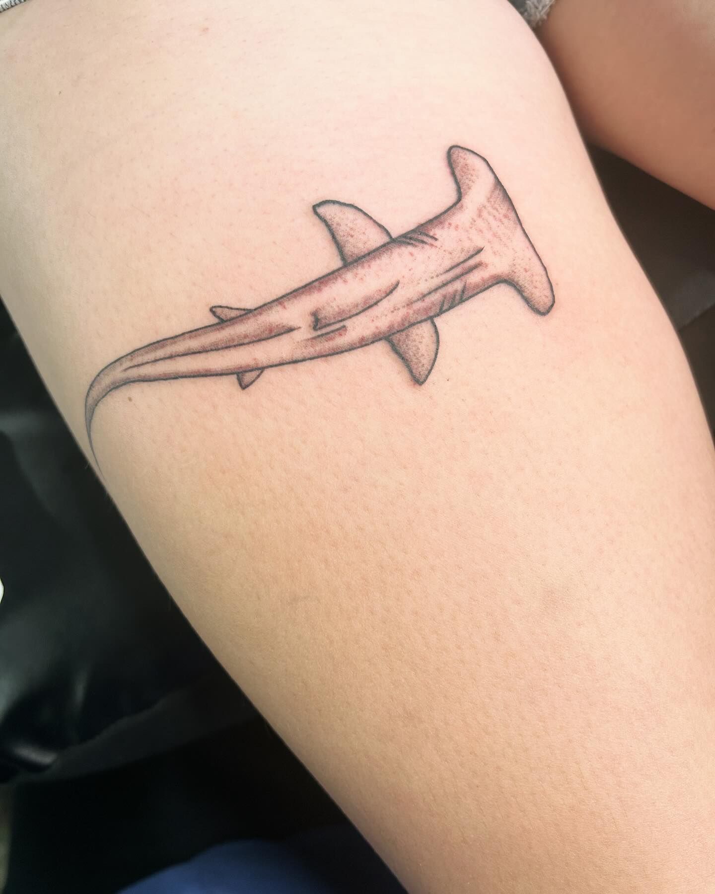 A person has a tattoo of a shark on their arm