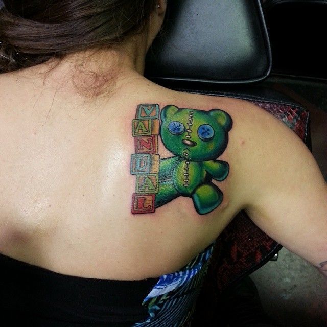 A woman has a teddy bear tattoo on her back