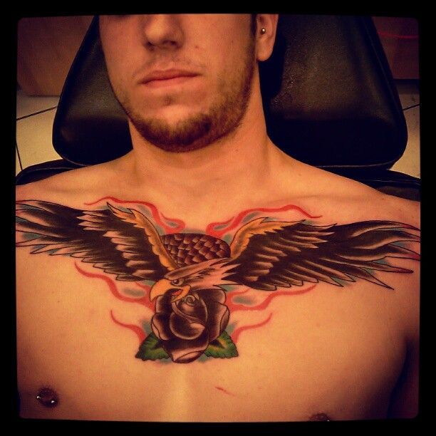 A man has a tattoo of an eagle and a rose on his chest