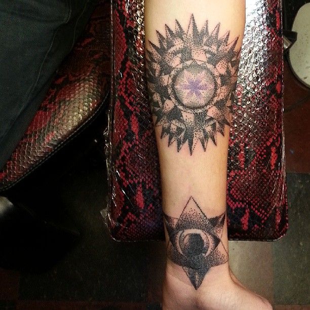 A person has a tattoo of a sun on their forearm