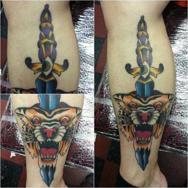 A person has a tattoo of a tiger and a dagger on their leg