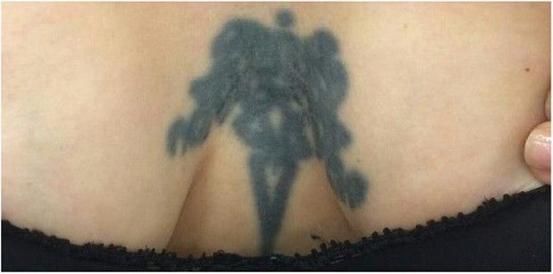 A woman has a tattoo on her back that looks like a shadow of a person.