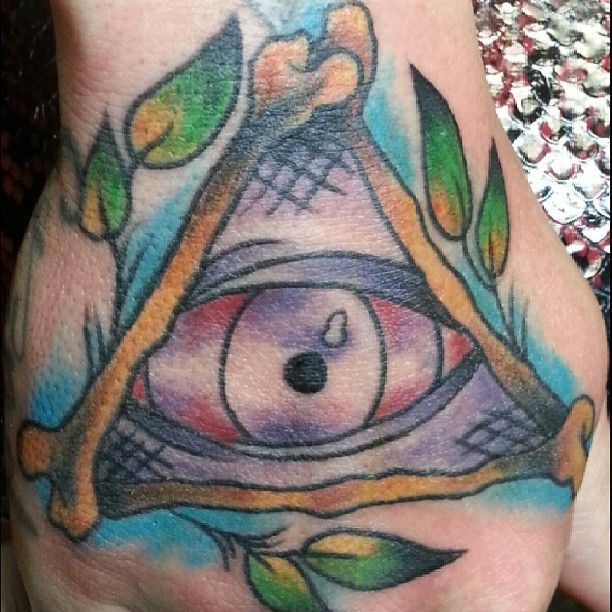 A person has a tattoo of an eye in a triangle on their hand.