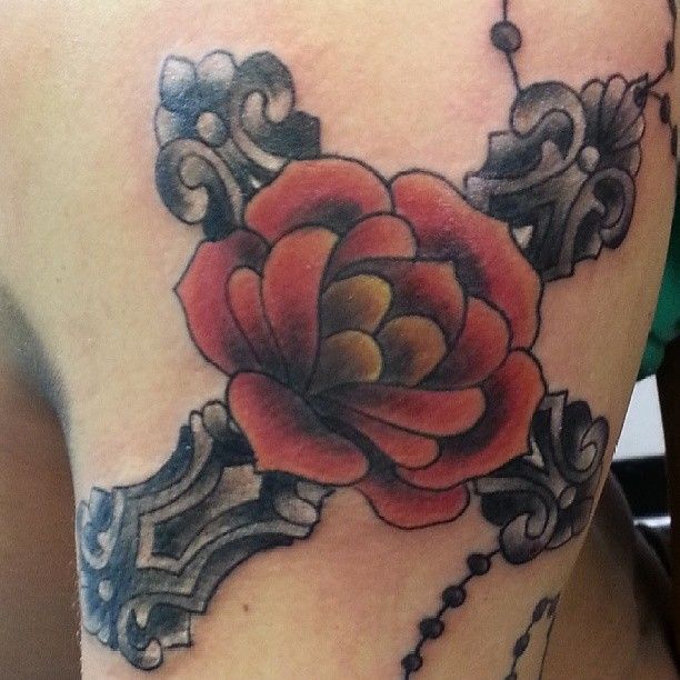 A tattoo of a cross with a red rose on it