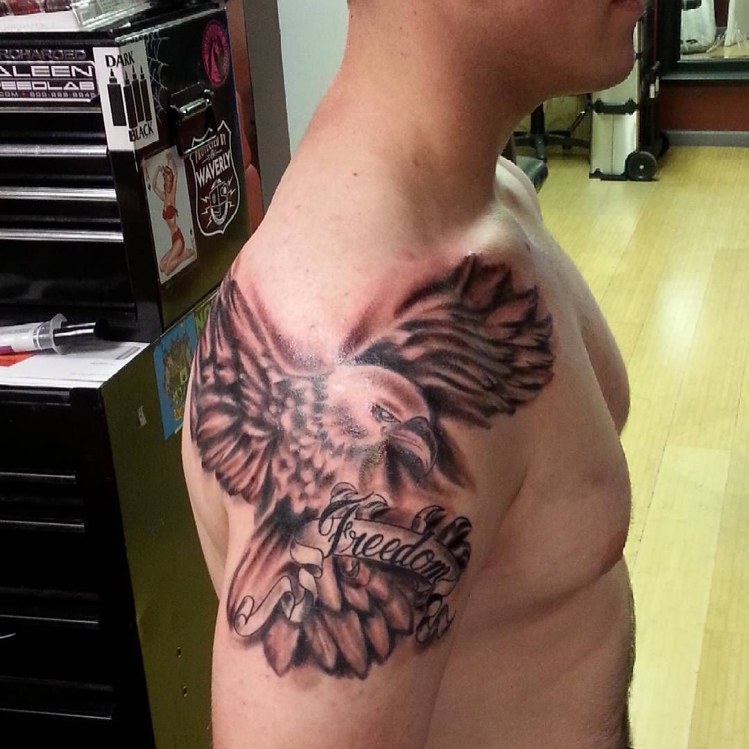 A man has a tattoo of an eagle and the word freedom on his shoulder