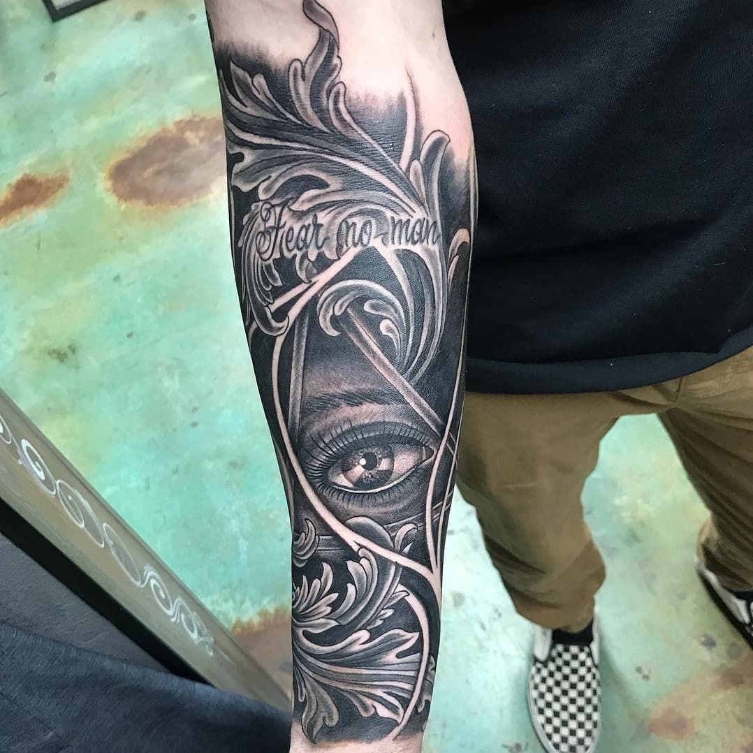A man has a tattoo of an eye on his forearm.