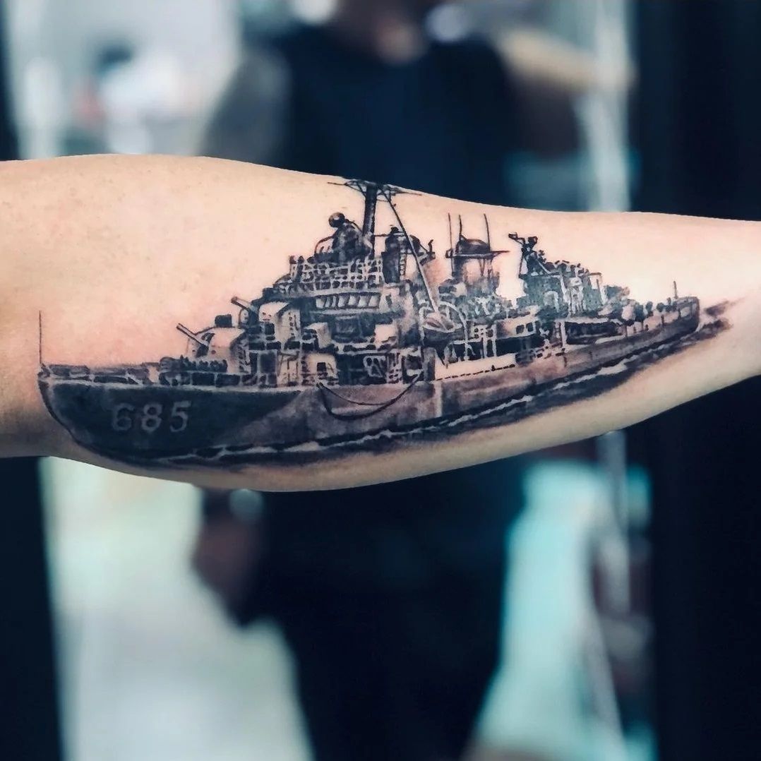 A person has a tattoo of a ship on their forearm
