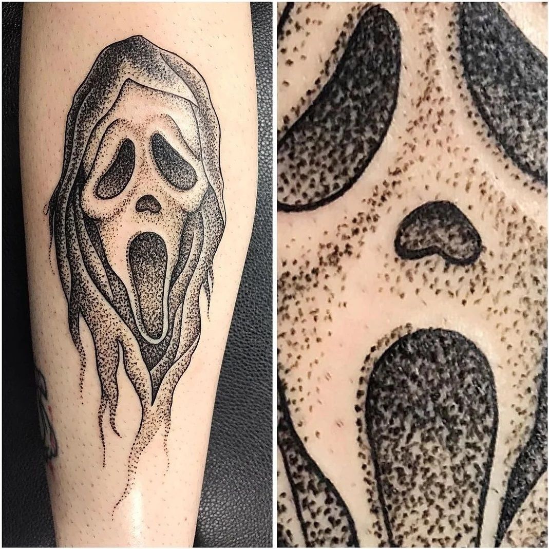 A black and white tattoo of a scream face on a person 's leg.