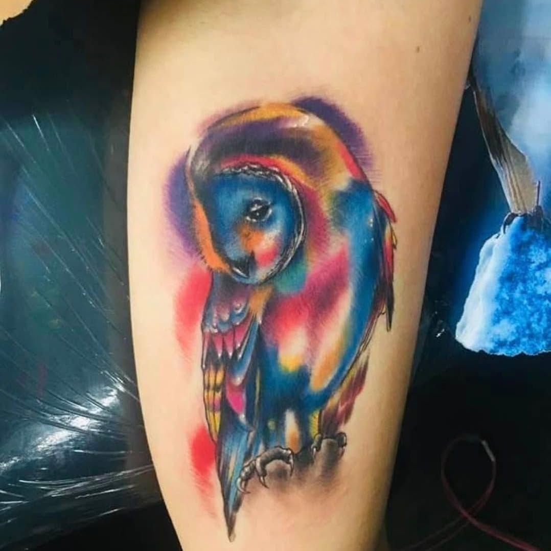 A woman has a colorful owl tattoo on her leg