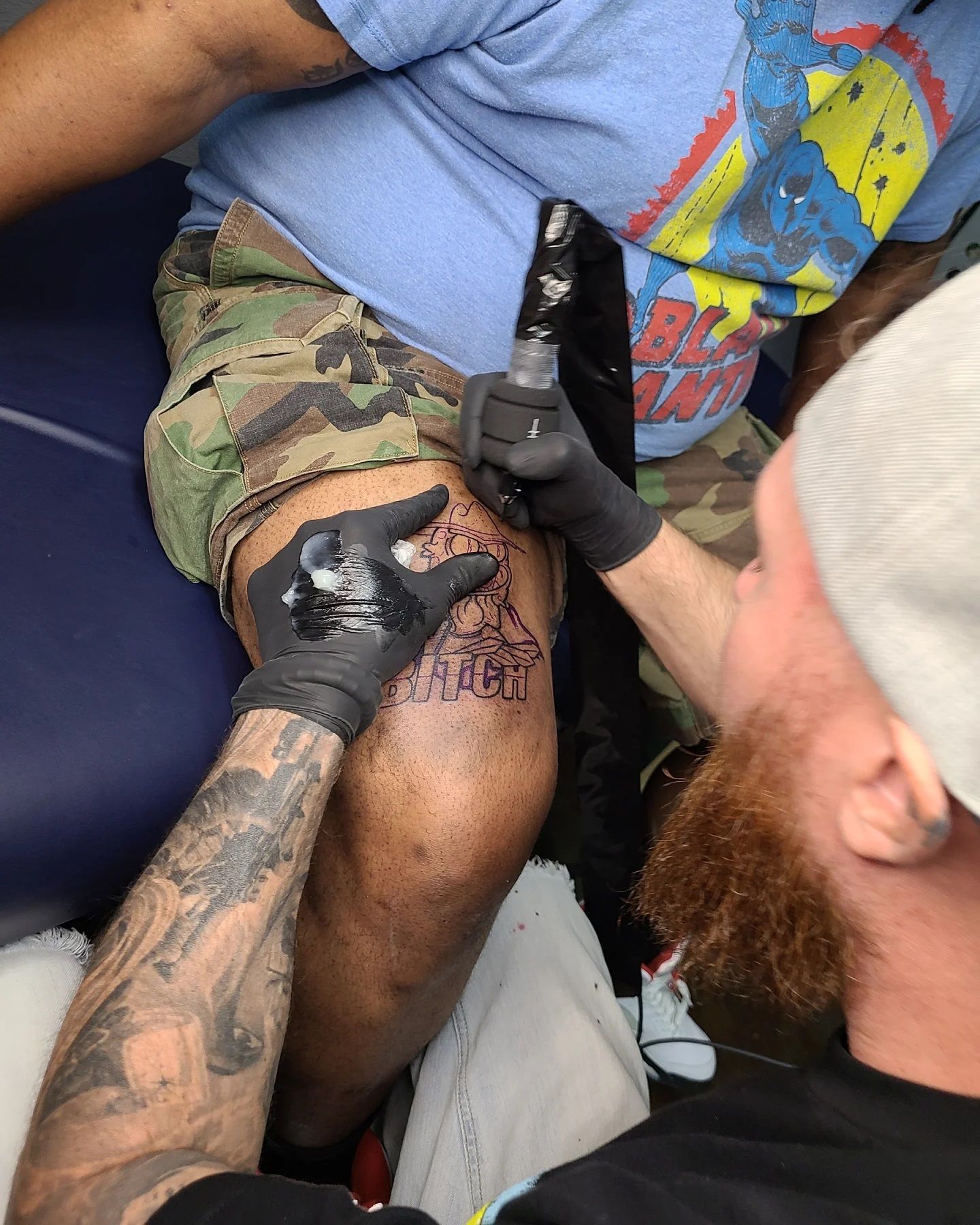 A man is getting a tattoo on his leg